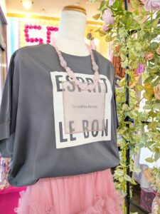 チャコールグレーのロゴTシャツにピンクのフリルスカートを合わせた大人のカジュアルスカートコーデ