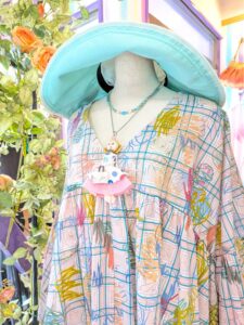 エターナリーブレイズのカラフルな柄トップスにグリーン系の帽子を合わせた、大人の華やかコーデ。